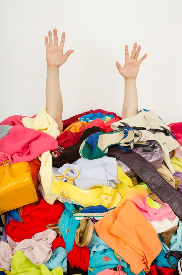 A photo of person buried under a pile of clothing with their hands in the air surrendering