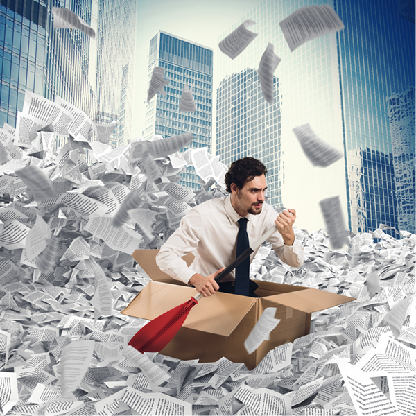 A determined looking DevOps engineer is sitting in a cardboard box as if it's a boat, with a paddle out the side. Instead of water, they are surrounded by pages and tickets of work to do